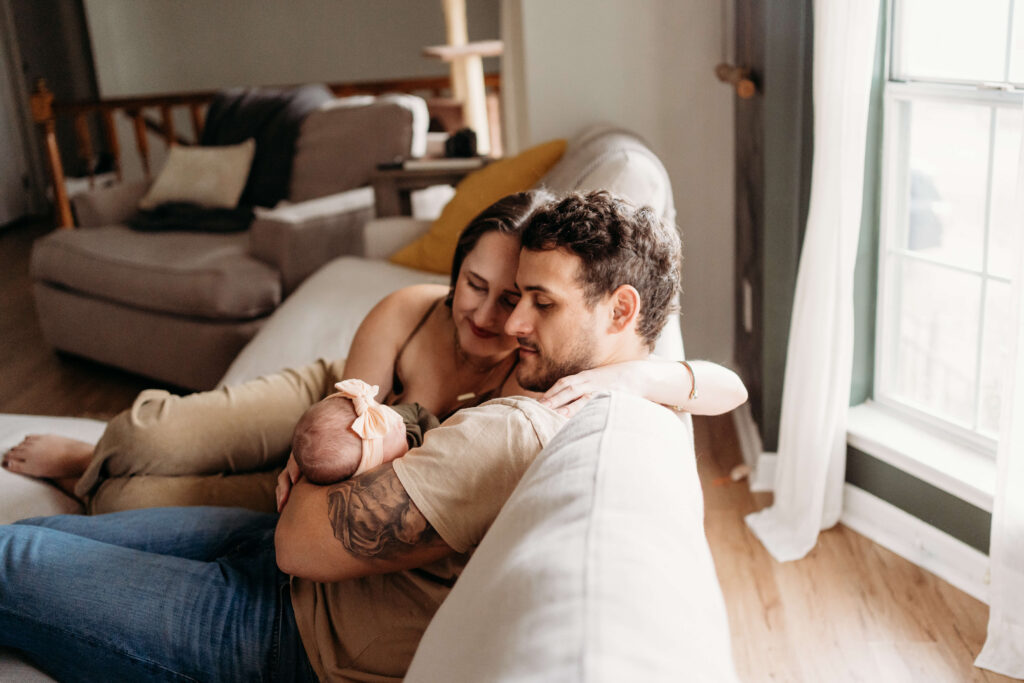 Mom, dad, and newborn on the couch.