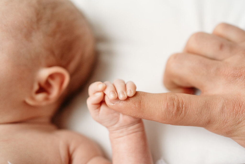 Mom holding babies finger.