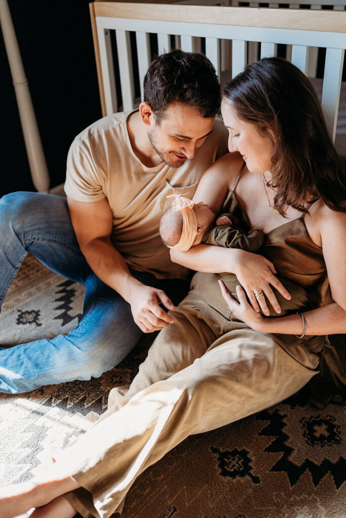 Mom and dad looking at baby during newborn photos.