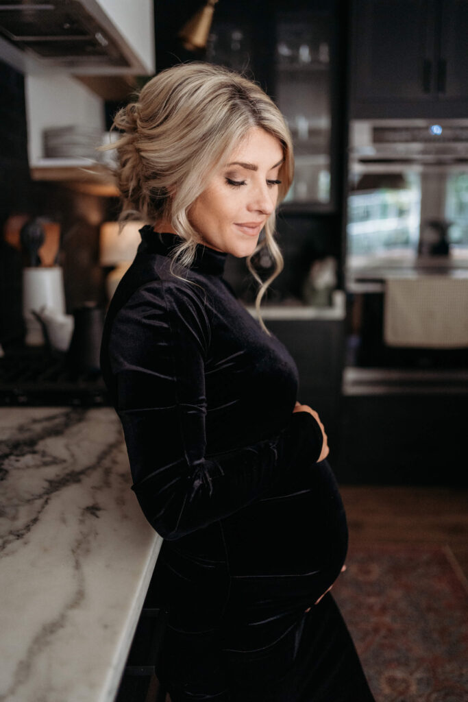 Beautiful mom to be holding her pregnant belly during time of maternity photos showing when to take maternity photos.