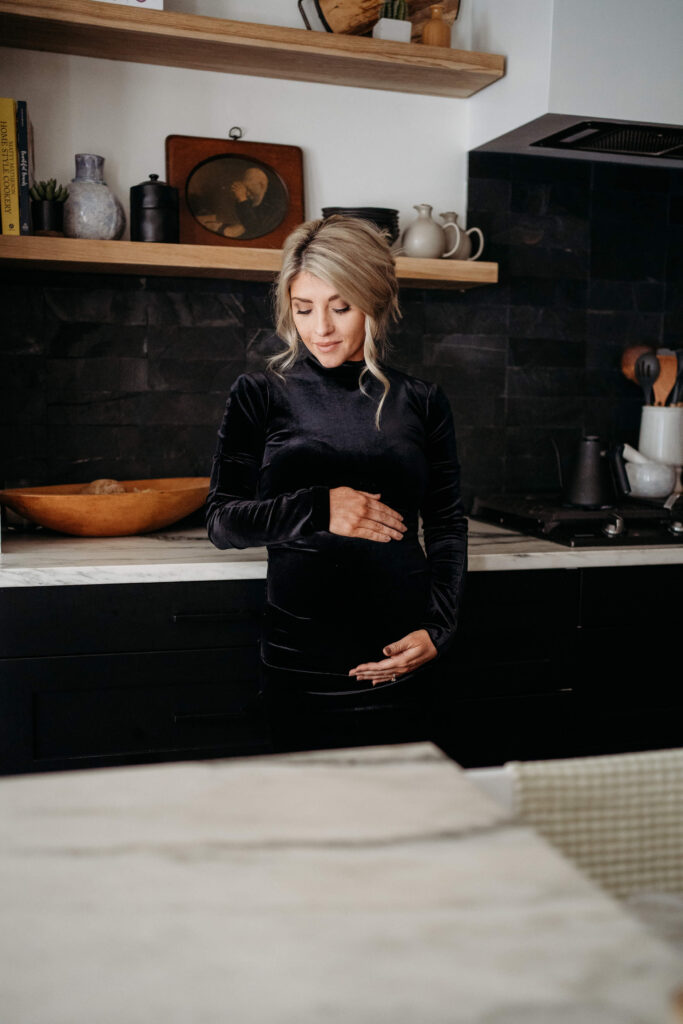 Expectant mom standing in kitchen showing when to take maternity photos.