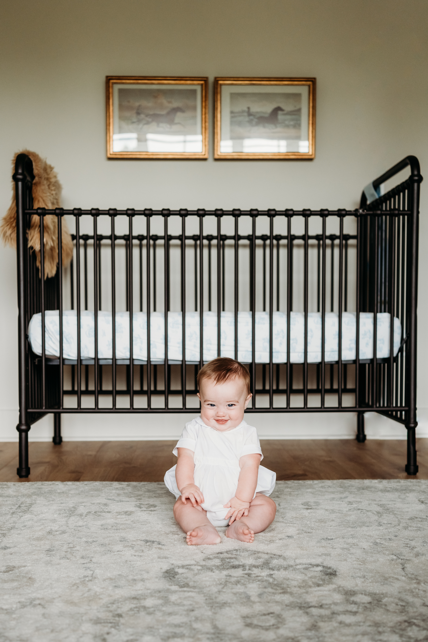 Baby smiling in front of the crib.