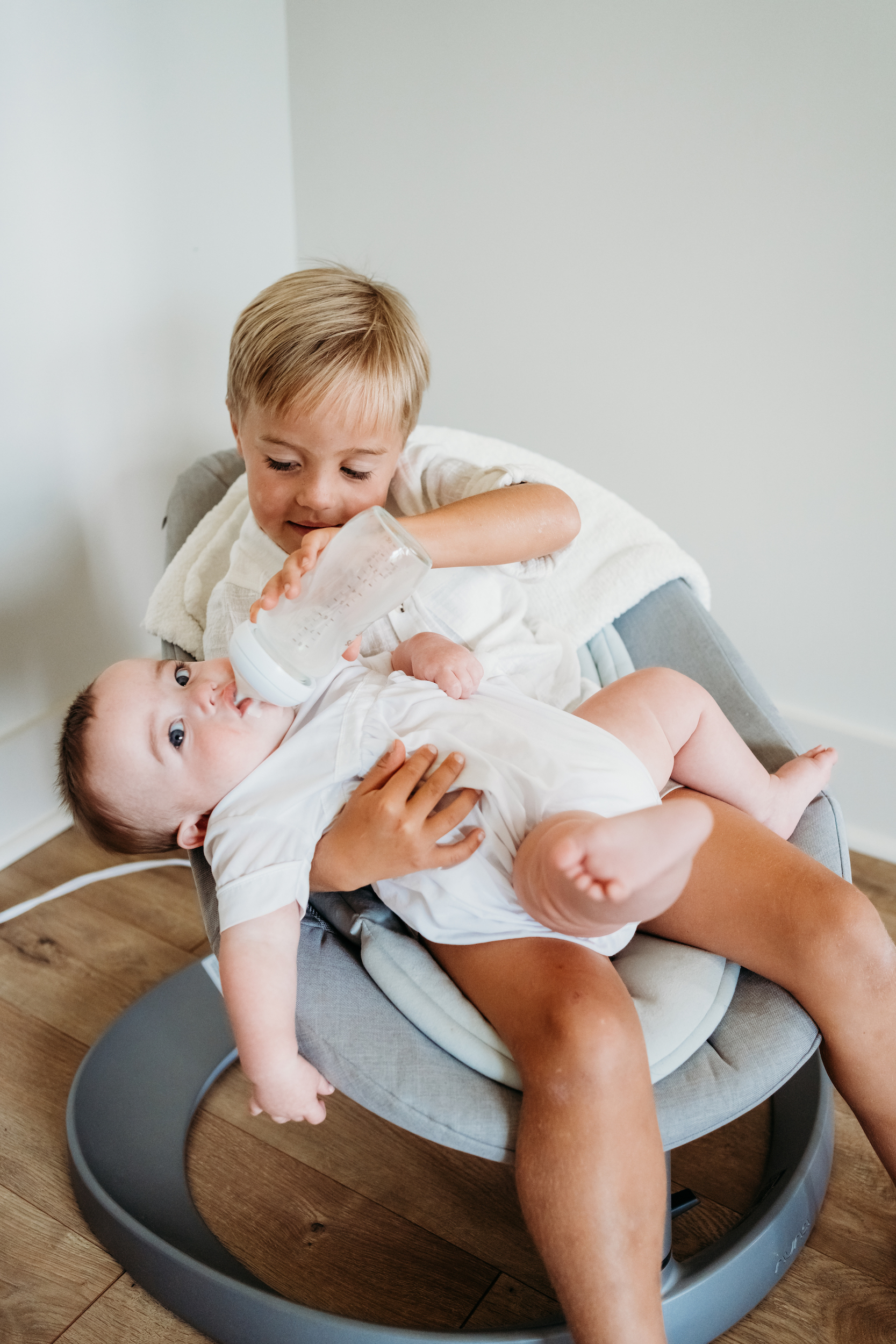 Big brother feeds little brother the bottle.