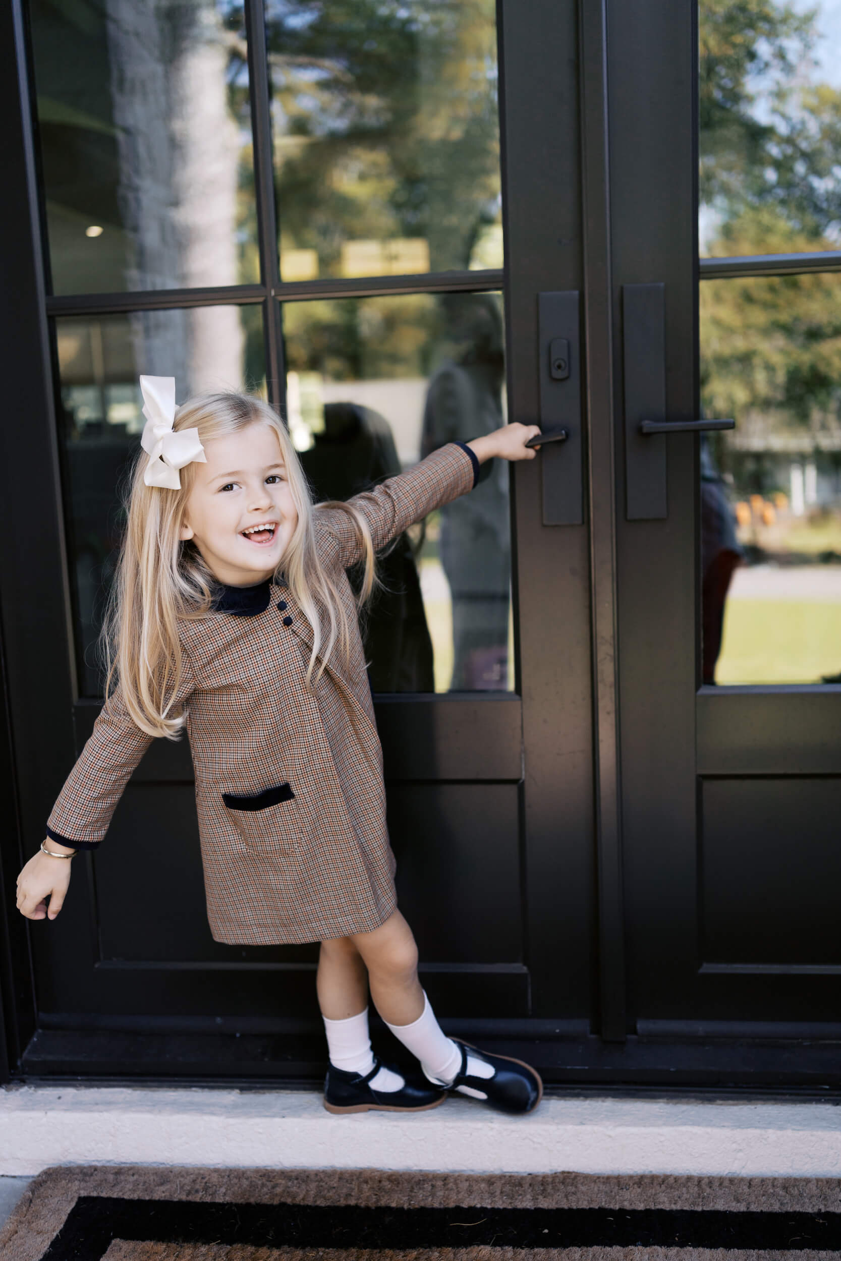 Girl swinging on the door knob while playing on the front porch.