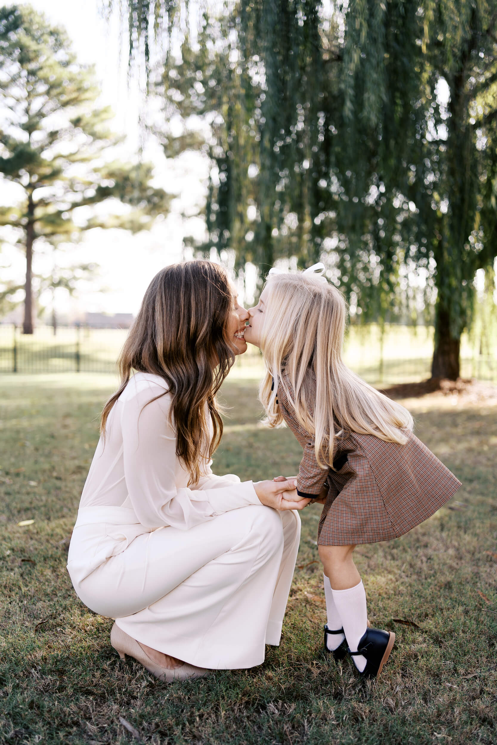 Daughter kissing mom in front of a tree after visiting Child's Play Therapy Center