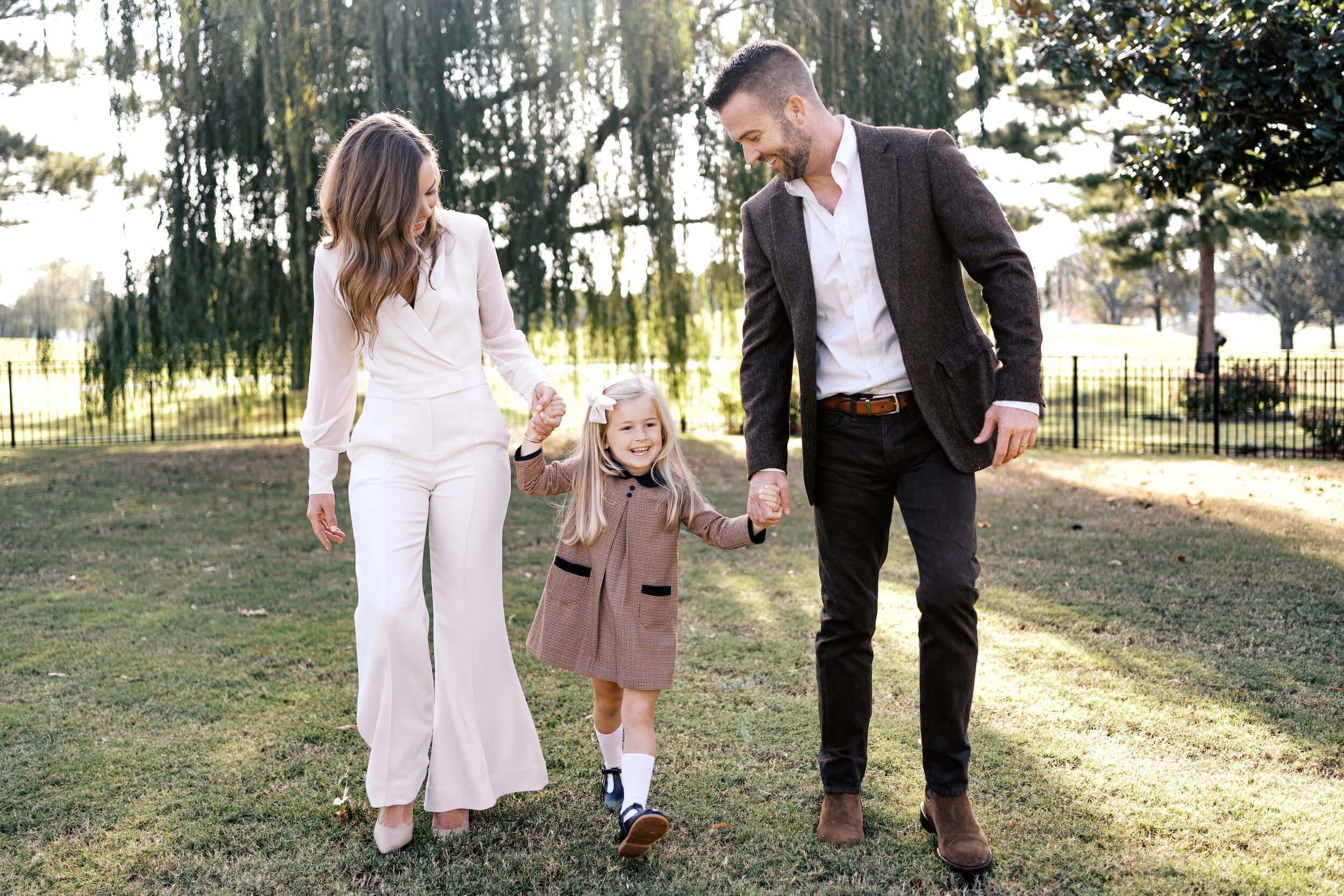 Family walks together smiling in the sunshine.